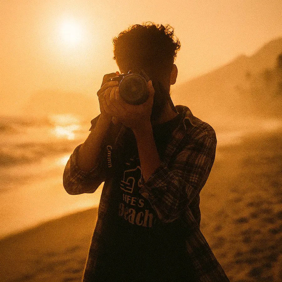 Md Aseer Intiser on a beach at sunset, holding a camera up to his eye